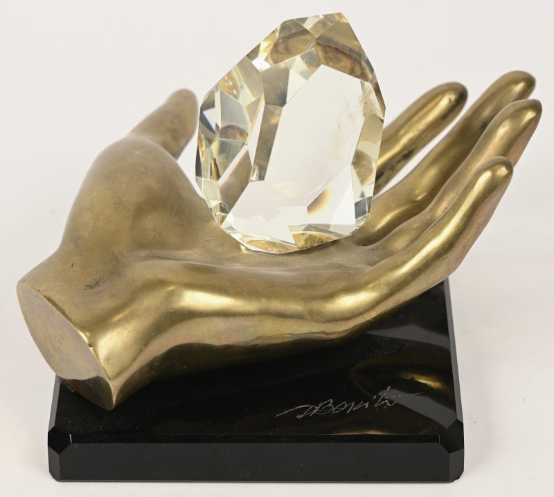 Een sculptuur van een bronzen hand met een kristal op zwart marmeren sokkel, gesigneerd Bonito. Met opschrift.