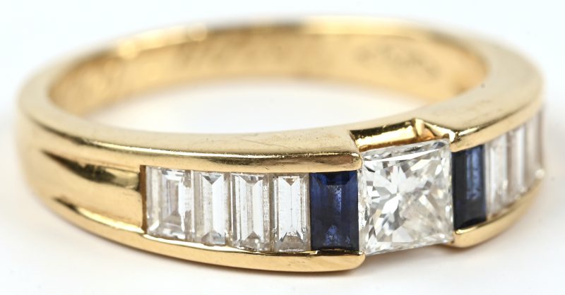 Een 18 karaats geelgouden ring bezet met een centrale diamant princes slijp van +- 0,30 ct. en diamant en twee saffier baguettes met een gezamenlijk gewicht van +- 0,80 ct.