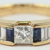 Een 18 karaats geelgouden ring bezet met een centrale diamant princes slijp van +- 0,30 ct. en diamant en twee saffier baguettes met een gezamenlijk gewicht van +- 0,80 ct.