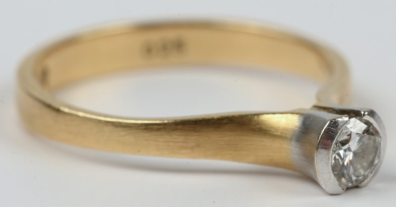 Een 18 kt wit en geelgouden ring bezet met een solitair van +- 0,25 ct.