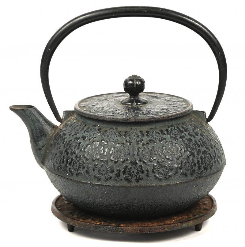 Chinese gietijzeren theepot, op onderzetter. Versierd met bloemendecor.