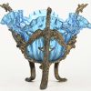 Blauwglazen organisch gevormde schaal, op driebenige vergulde metalen voet. Versierd met grifoenen en andere fabeldieren.