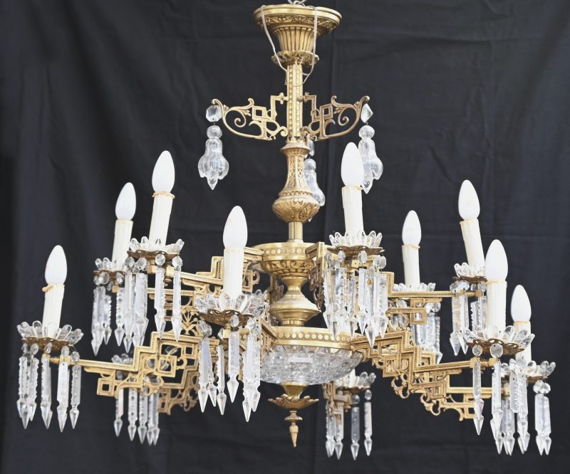 Een vroeg 20ste eeuwse vergulde Art Deco luchter met 12 rechtgehoekte lichtarmen en uitvoerige kristallen pendeloques. Met verloopstukken om de luchter een niveau te verhogen, en reservestukken.
