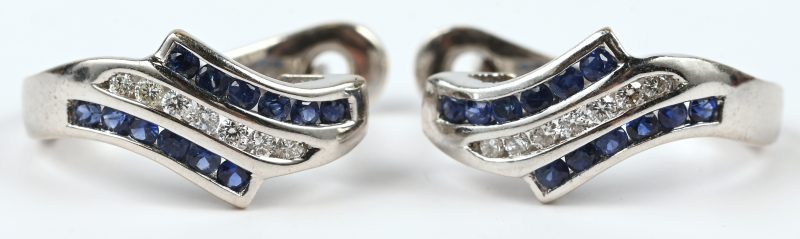 Een paar 18 kt wit gouden oorbellen bezet met briljanten met een gezamenlijk gewicht van +- 0,14 ct. en saffieren met een gezamenlijk gewicht van +- 0,24 ct.
