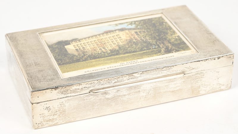 Een zilveren sigarettendoos, gemerkt ‘Sterling 925’, met houten inzet en een foto ‘125 jahre Kölnische Rückversicherungs-Gesellschaft.
