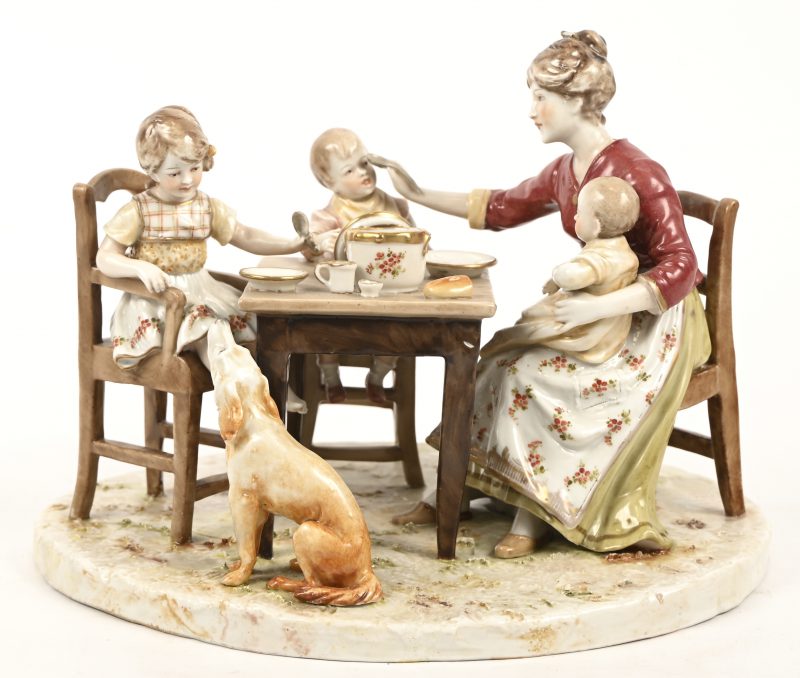 “Aan tafel”, een porseleinen groep voorstellend een moeder met 3 kinderen en hond. Kleine schade aan het haarstuk van de moeder. Gemerkt met een gekroonde F.