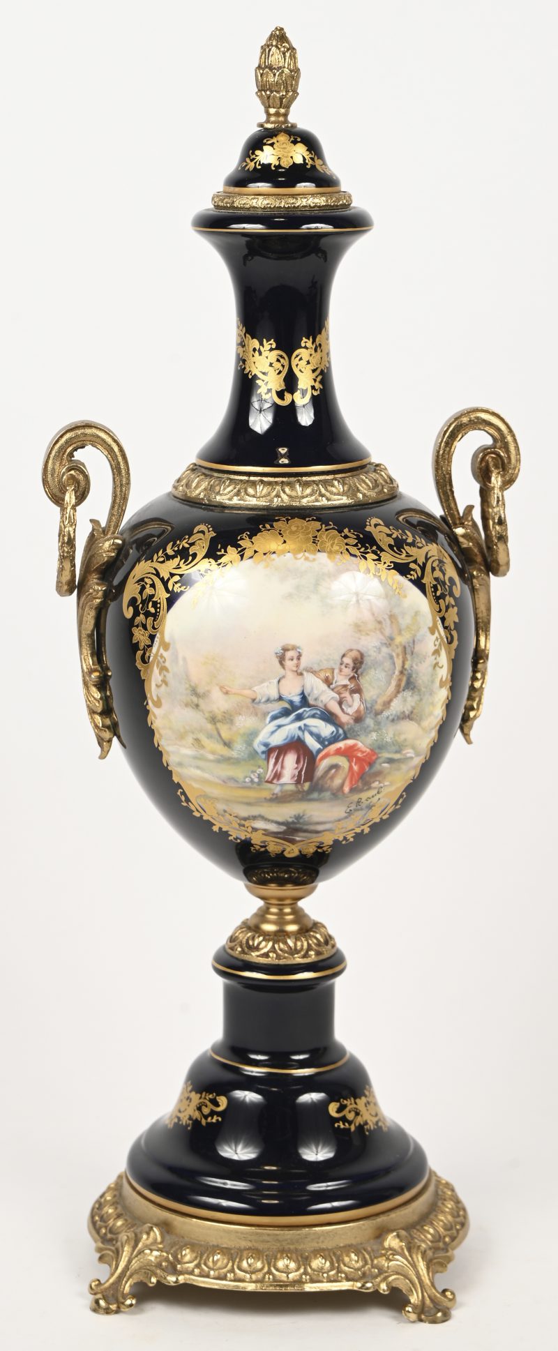 Een kobaltblauwe vaas met vergulde en verguld metalen details, versierd met een romantische scène in een uitsparing. Naar Sèvres voorbeeld. Onderaan gemerkt.