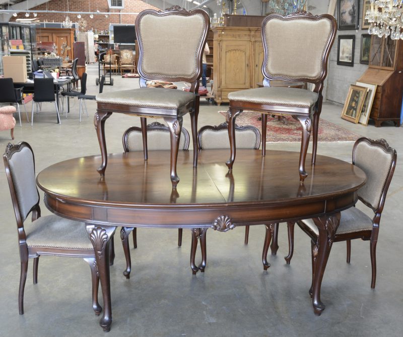 Een verlengbare ovale eetkamertafel en zes bijpassende stoelen versierd met schelpenmotief naar Chippendale voorbeeld. Stoelen met fluwelen bekleding.