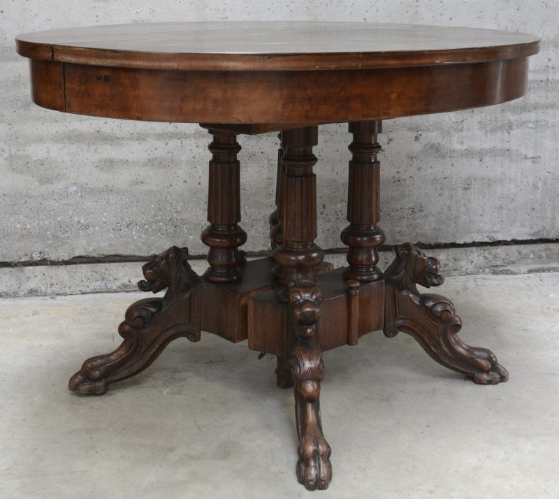 Een verlengbare ronde eetkamertafel met een centrale vierpoot versierd met vossenkoppen.