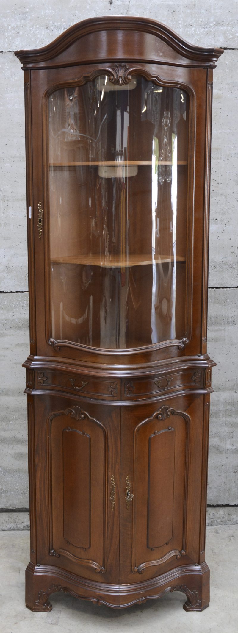 Een hoekvitrine naar Engels voorbeeld. Dubbelgebogen front.
