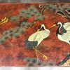Een salontafel versierd in Chinese lak met reigers bij een vijver op rode fond. Poten in een doorlopende krul. Lichte slijtage.