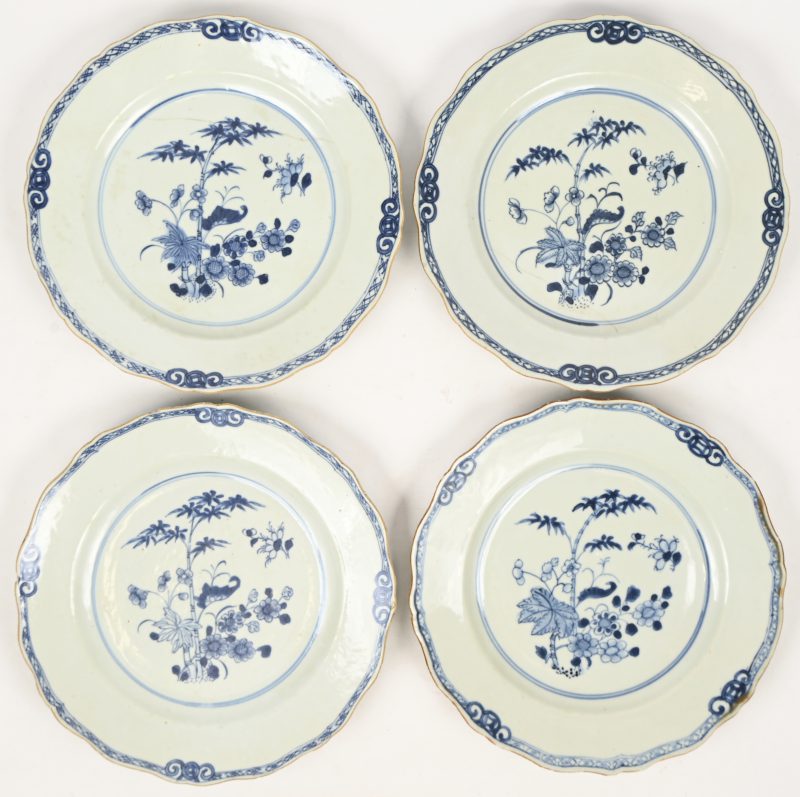 Vier borden van Chinees porselein met een blauw op wit decor van flora. Qianlong decor. 2 borden met grote haarlijnscheur.
