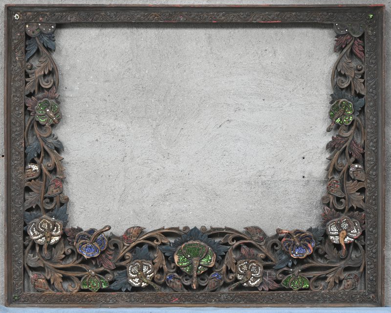 Een Oosterse geajoureerde lijst met een bloemenmotief en met gekleurde glazen details.