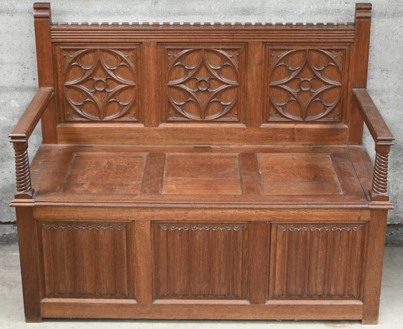 Een eikenhouten kofferbank in gotische stijl met spitsbogen en perkamentpanelen versierd.