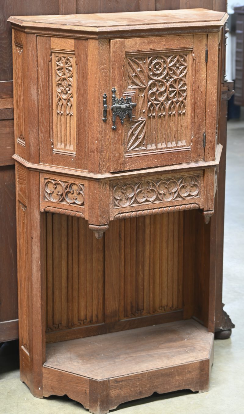 Een gebeeldhouwde eikenhouten credenza met één deur bovenaan. Spitsbogen en perkamentpanelen in gotische stijl.
