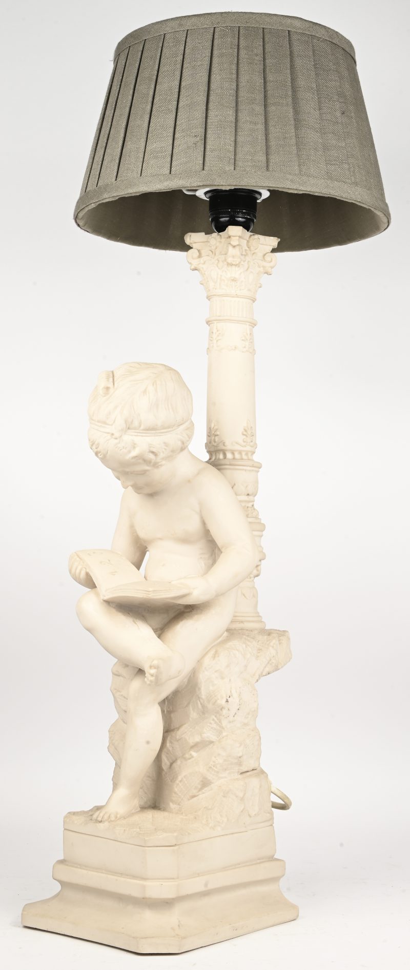 Een tafellamp met een lezende putto van kunsthars zittend op een rots.