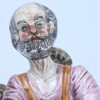 Een meerkleurig beeld van een schoenmaker in porselein, gemerkt Capodimonte. Toegevoegd een meerkleurig beeld van een meisje in biscuit.