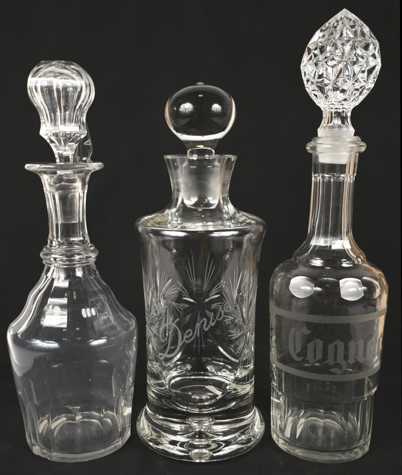 Lot van drie karaffen, waarvan 1 met het opschrift ‘COGNAC’ en een geslepen Boheemse karaf met de gegraveerde naam ‘Denise’, met schilferschade aan de rand.