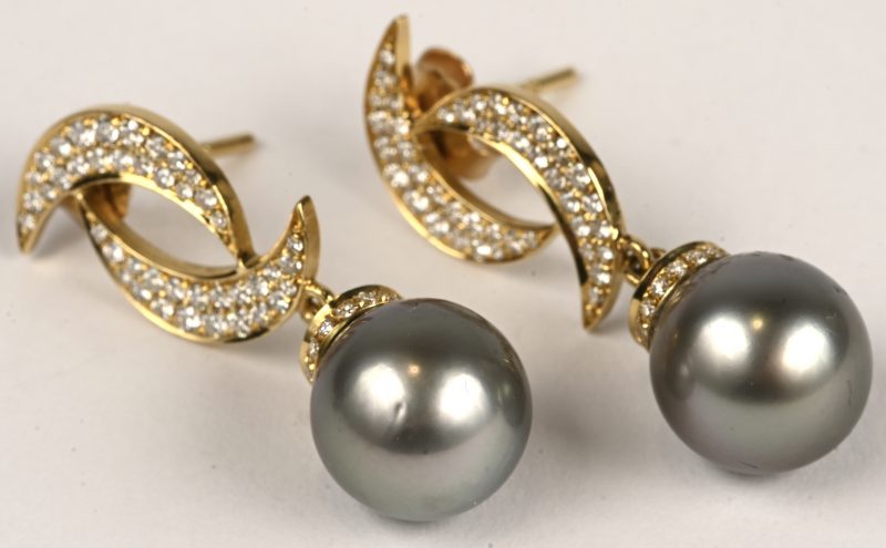 Een paar 18 kt geelgouden oorbellen bezet met briljanten met een gezamenlijk gewicht van +- 1 ct. F VVS-VS. En twee grijze parels van 11mm.