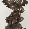 Een bronskleurige zamak bloempothouder met een putti als voet. Restauratie aan de bovenrand.