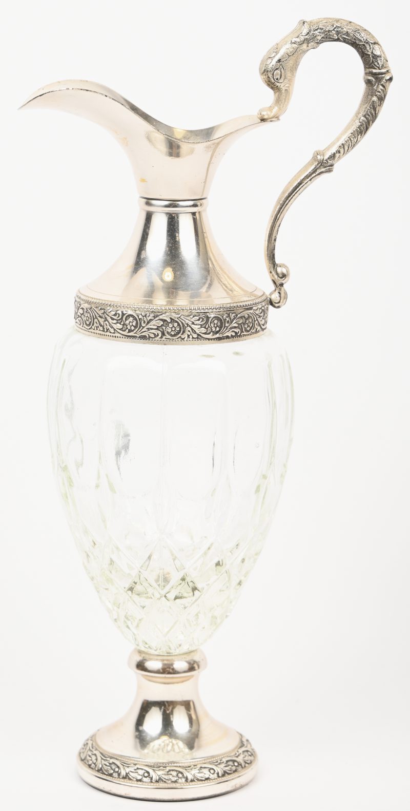 Een schenkkan van gegoten kristal met verzilverde tuit, voet en handvat.