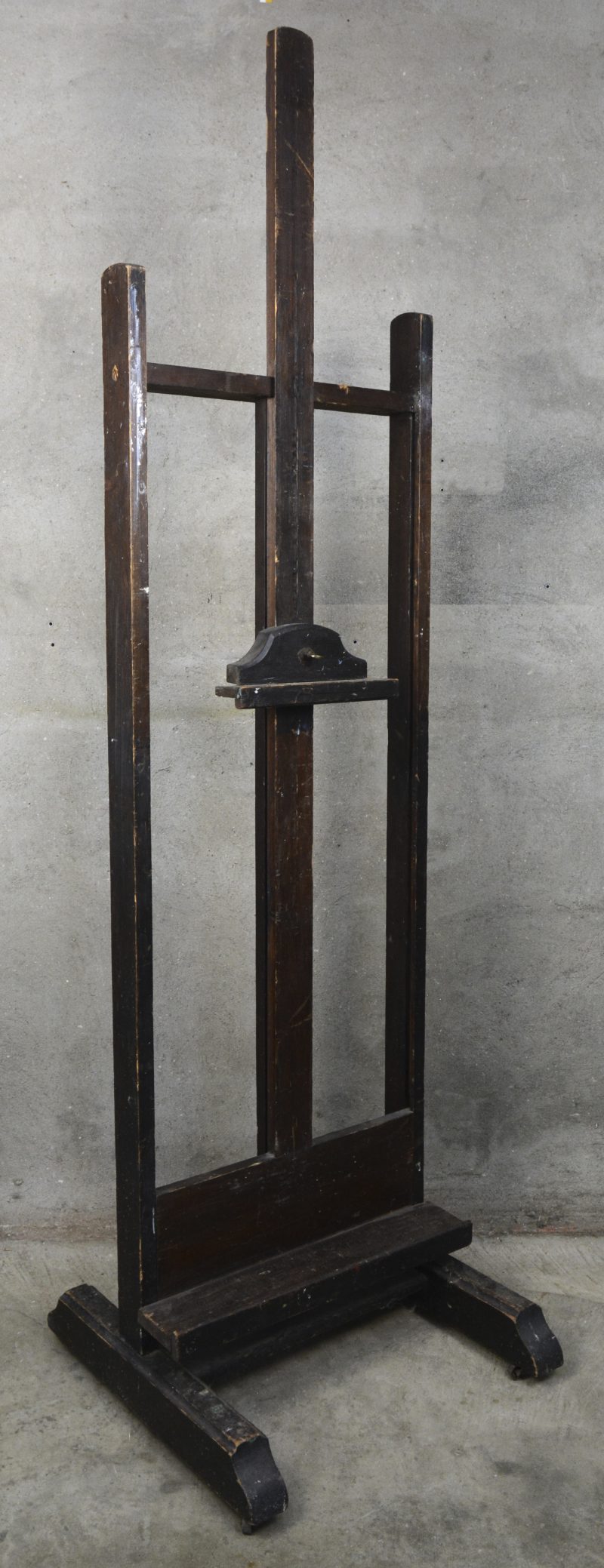 Een massief houten schildersezel. De grendel om de hoogte in te stellen is manco.