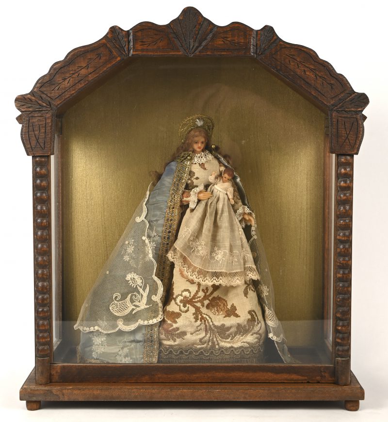 Een oude wassen madonna in houten vitrine.
