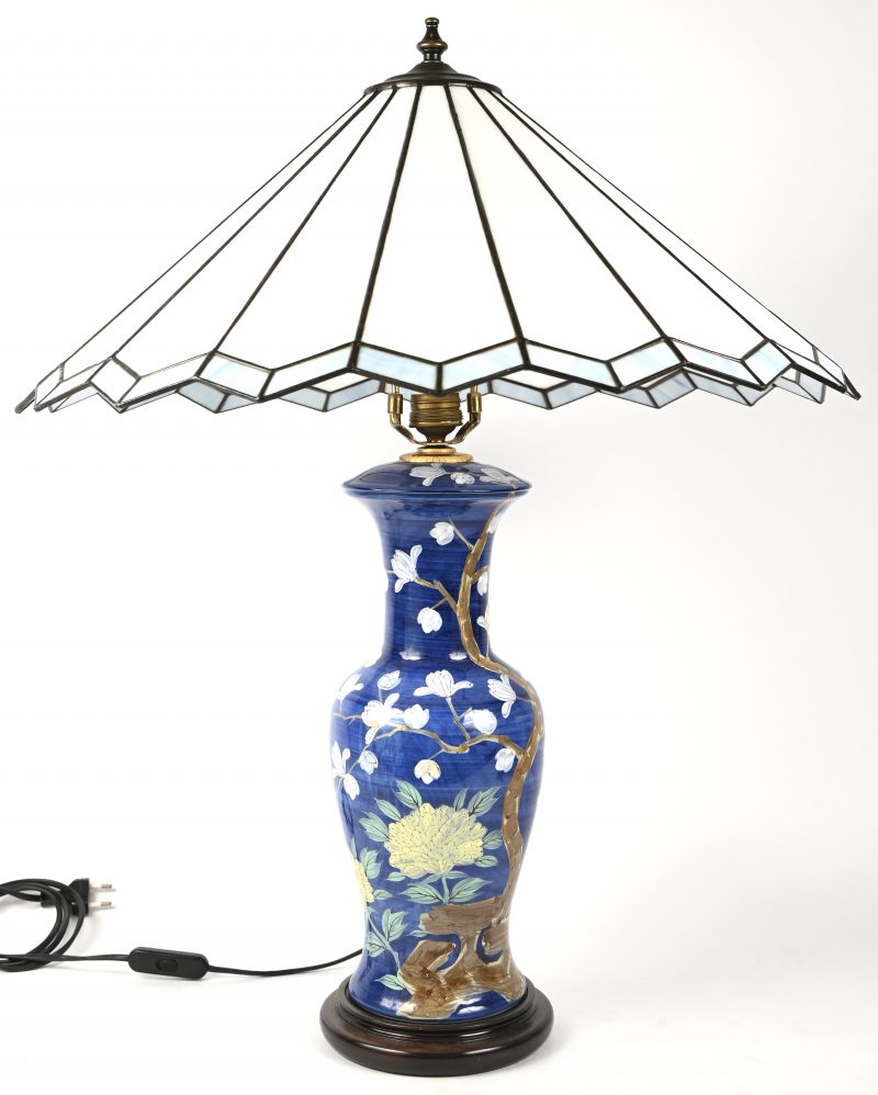 Een blauwe handbeschilderde lampvoet met floraal decor en glas-in-lood kap in Tiffany stijl.