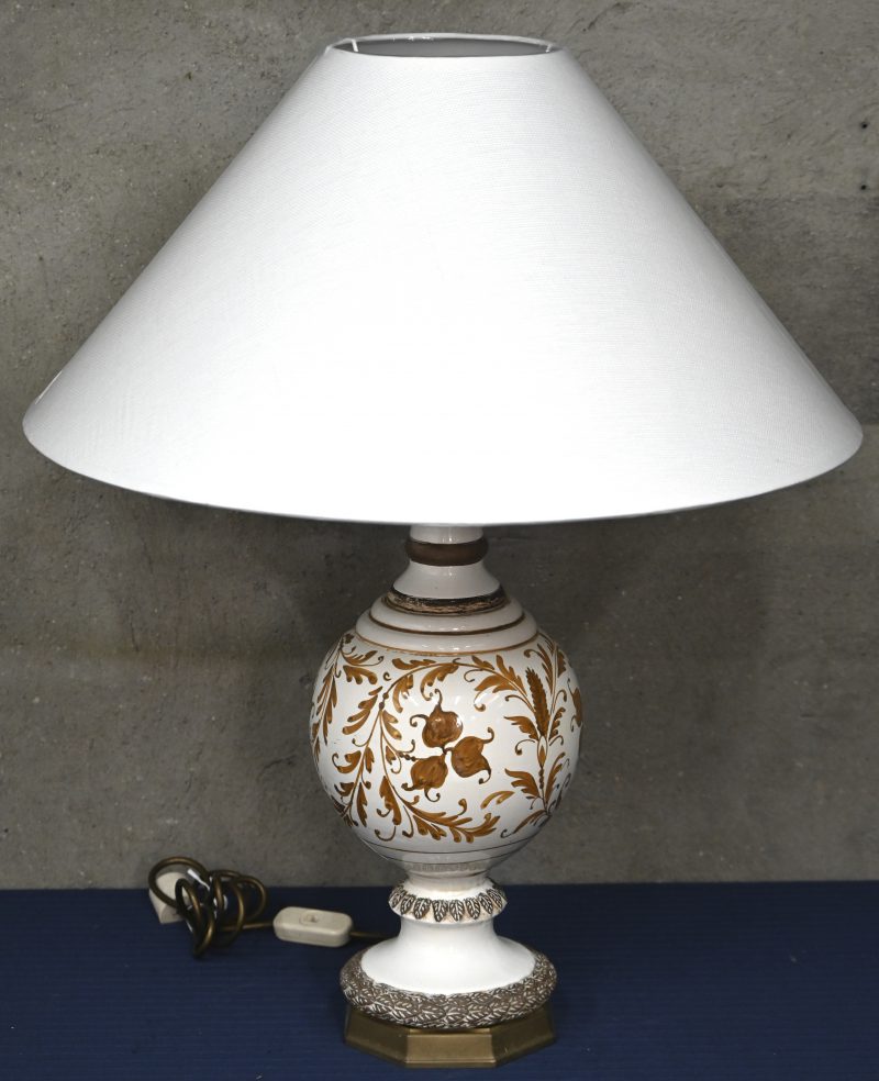 Een geglazuurd keramische lampenvoet met florale motieven en witte stoffen kap.
