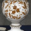 Een geglazuurd keramische lampenvoet met florale motieven en witte stoffen kap.