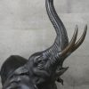 Een bronzen olifant met opgeheven slurf.