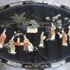 Een ovale Chinese salontafel van zwartgelakt hout met een decor van pietra dura onder glas.