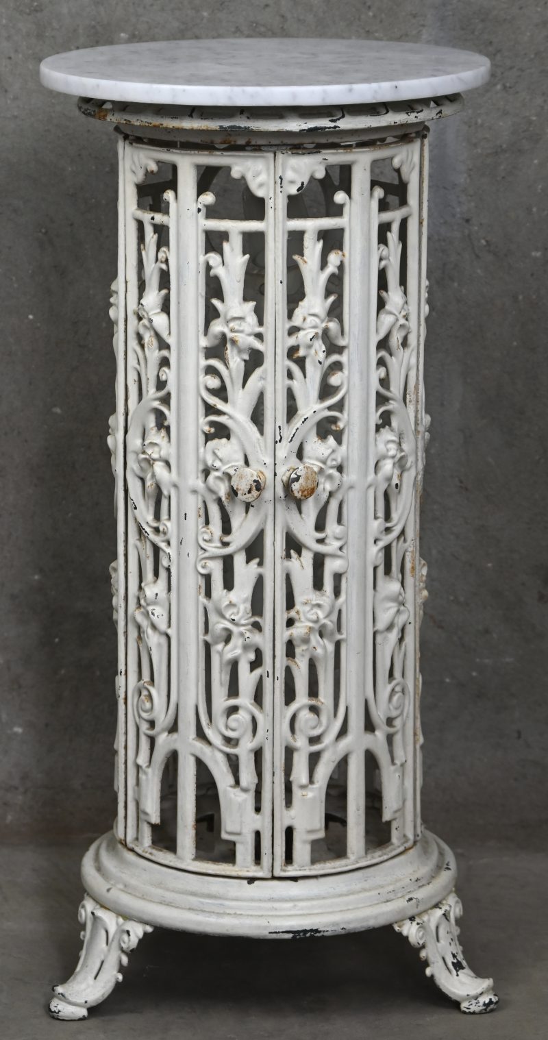 Een gietijzeren kacheltje, omgebouwd tot piëdestal met verlichting. Met wit marmeren blad.