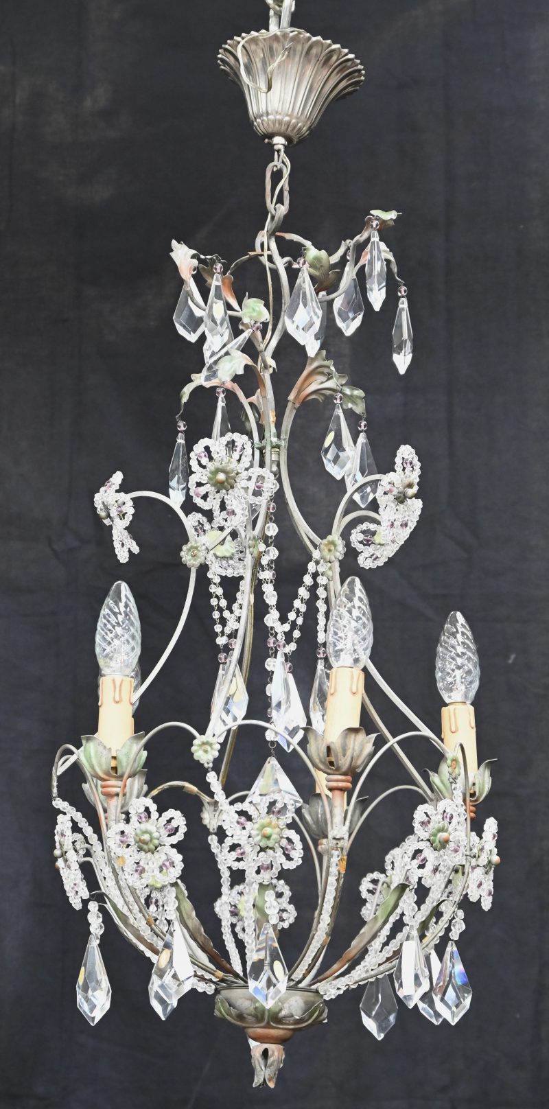 Een polychrome metalen luchter met florale decoratie en kristallen bellen.