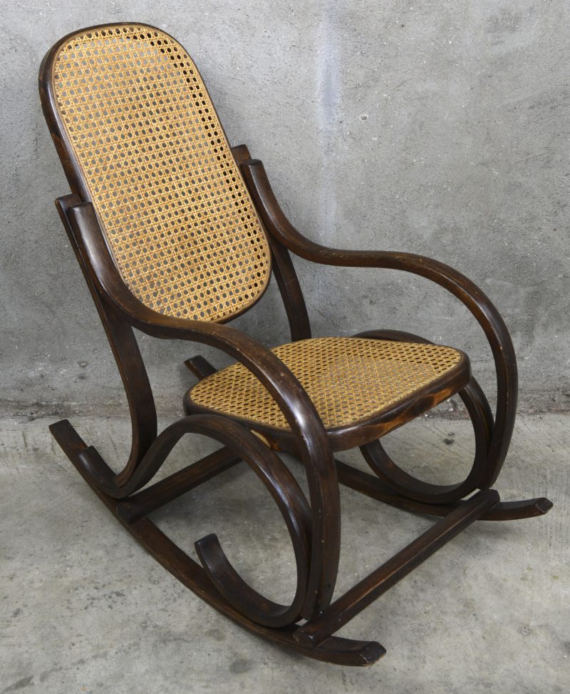 Een vintage kinderschommelstoel met gevlochten zitting en rugleuning.