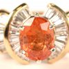 Een 14 kt wit en geelgouden ring bezet met diamant baguetten met een gezamenlijk gewicht van 1,08 ct. en een Brasiliaanse naranja saffier van 1,64 ct. Met certificaat.