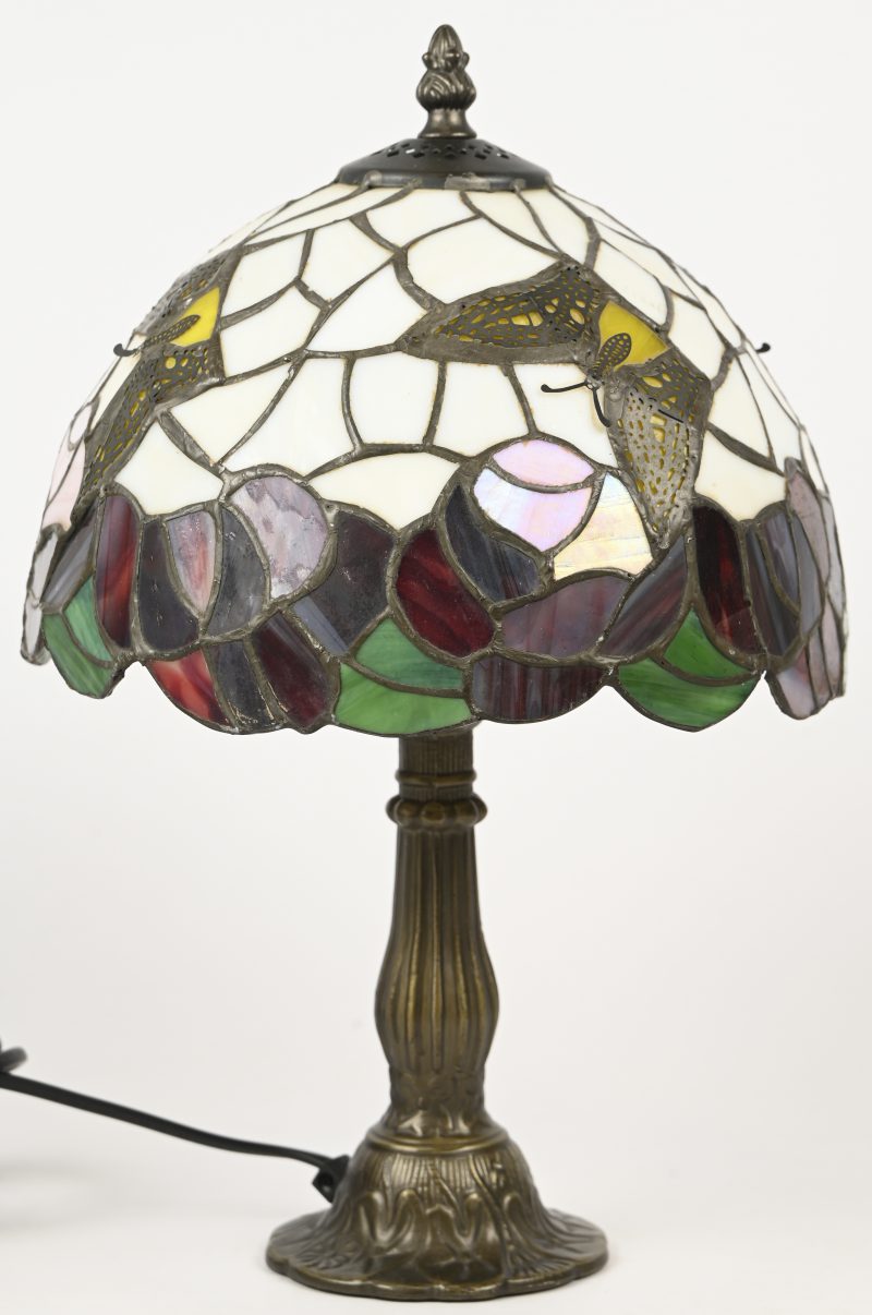 Een tafellampje met kap in Tiffany stijl, met een bronzen voet. Met gele vlinders in het decor.