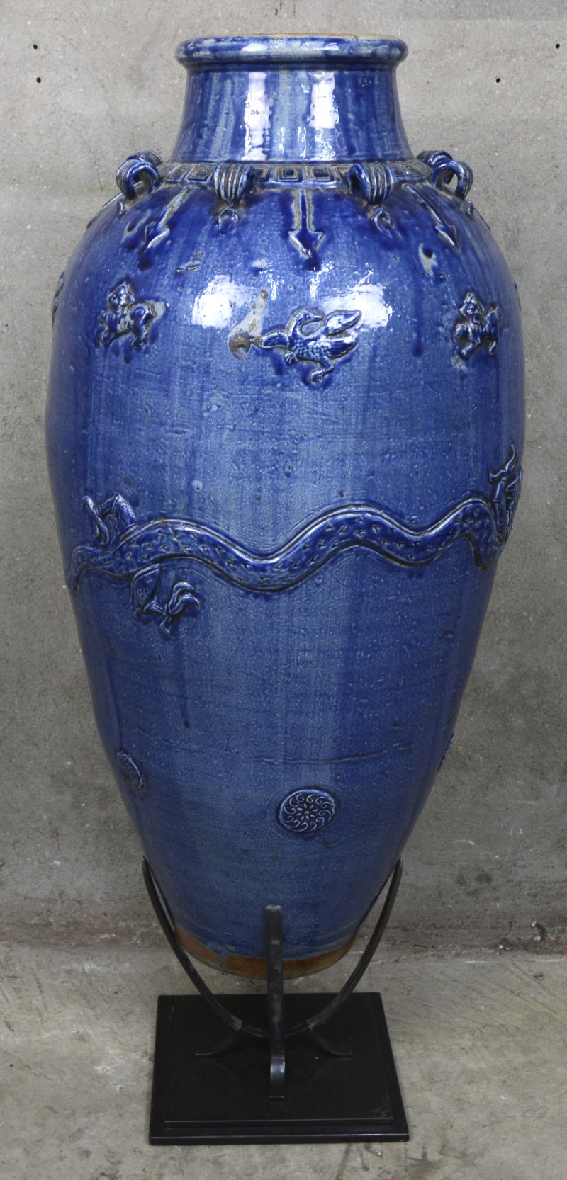 Een Chinese blauw geglazuurde aardewerken Martaban vaas op metalen staander.