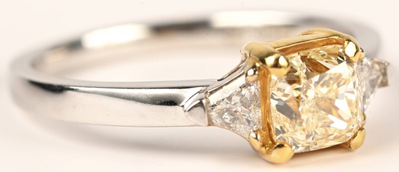 Een 18 kt wit- en geelgouden ring bezet centrale fancy intense yellow cushion briljant 0,70 ct. VVS1, en twee driehoekige briljanten met totaal gewicht van 0,26 ct. EVVS1.