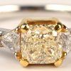 Een 18 kt wit- en geelgouden ring bezet centrale fancy intense yellow cushion briljant 0,70 ct. VVS1, en twee driehoekige briljanten met totaal gewicht van 0,26 ct. EVVS1.