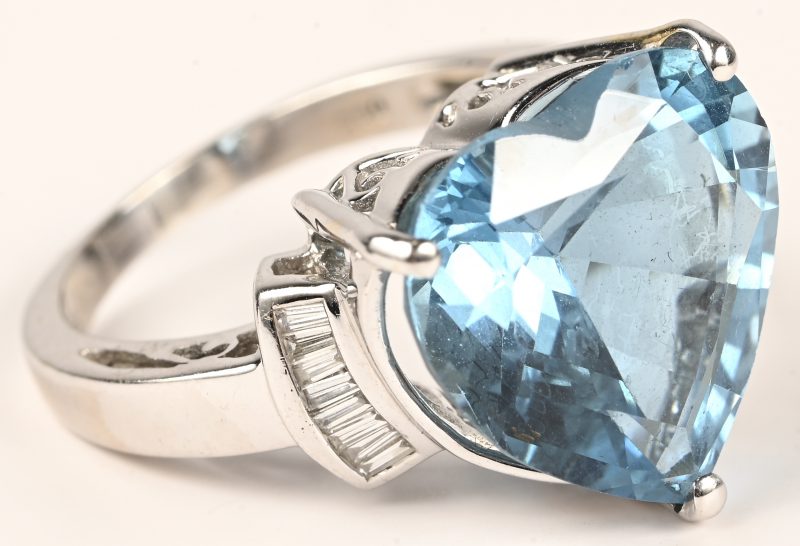 Een 18 kt witgouden ring bezet met briljanten met centrale hartvormige topaas van 11,7 ct. en baguetten met een gezamenlijk gewicht van 0,24 ct. Met certificaat.