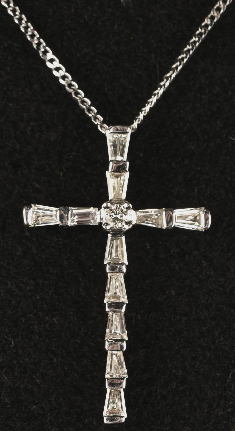 Een 18 kt witgouden ketting met crucifix hanger met baguetten met een gezamenlijk gewicht van 0,68 ct.