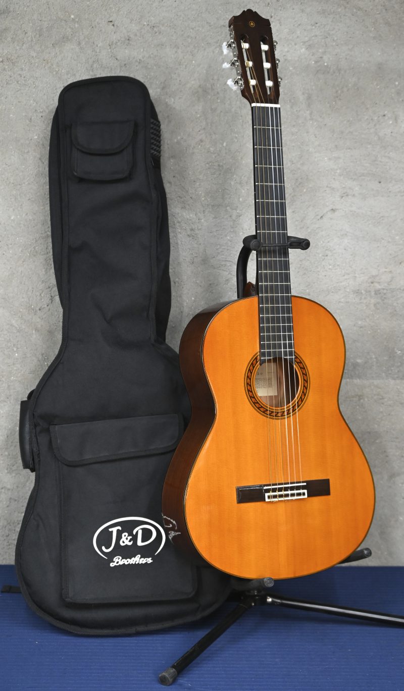 Een klassieke gitaar, Yamaha CG 120, met staander en draagtas.