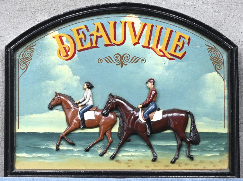 Een houten hangbord in basse-relief, met twee ruiters en het opschrift; DEAUVILLE.
