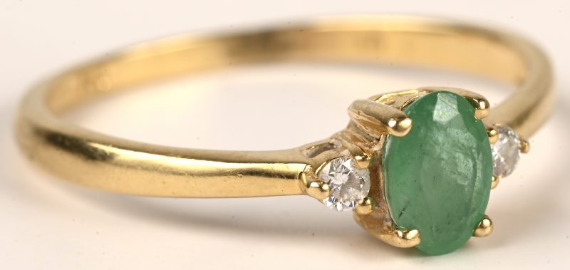 Een 18 kt geelgouden ring bezet met twee kleine briljantjes en een Columbiaanse smaragd van +- 0,25 ct.