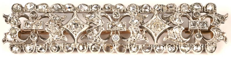 Een 18 kt witgouden en zilveren broche bezet met diamanten oude slijp met een gezamenlijk gewicht van +- 1 ct. (twee steentjes ontbreken).