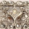 Een 18 kt witgouden en zilveren broche bezet met diamanten oude slijp met een gezamenlijk gewicht van +- 1 ct. (twee steentjes ontbreken).