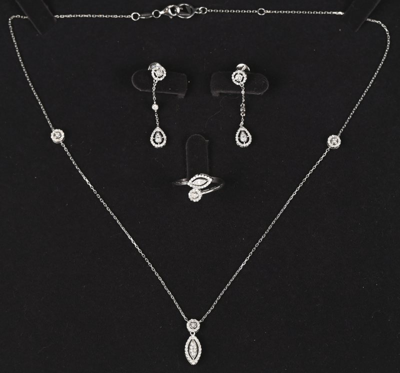 Een 18 kt witgouden parure waaronder ketting met hanger bijpassende oorbellen en ring bezet met briljanten met een gezamenlijk gewicht van +- 1 ct.