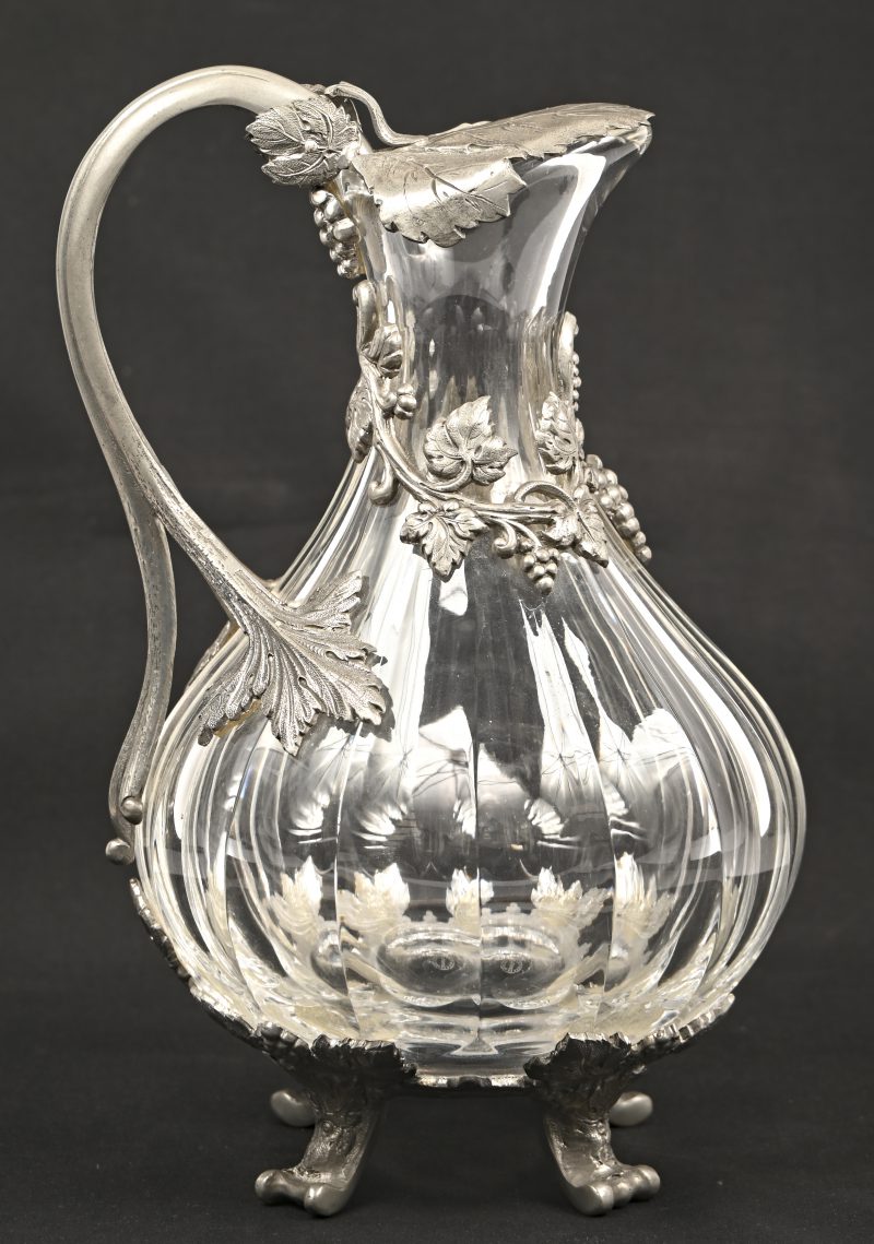 Een kristallen karaf, gemerkt Cristal St. Louis France, met tinnen druivenranken, deksel en voetjes.