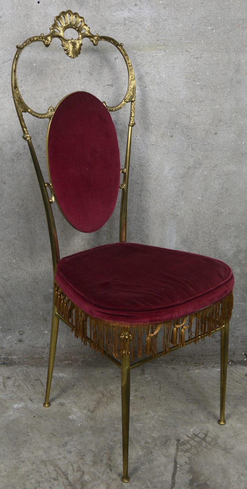 Een Hollywood Regency stijl stoel, messing en bordeauxrode velours bekleding, midden de tweede helft van de vorige eeuw.